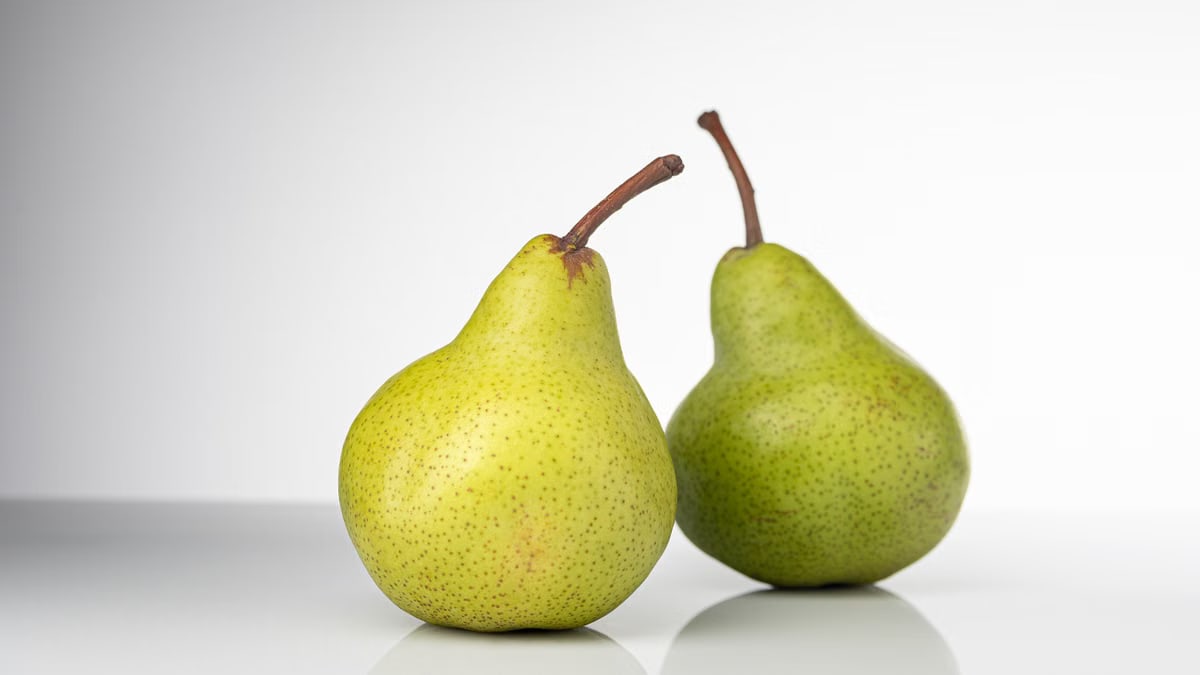 Bright and fresh green pears on a clean white background, symbolizing healthy eating and fresh produce.