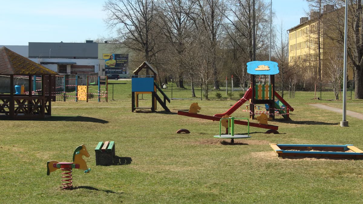 An empty urban playground with colorful equipment under clear skies in spring.